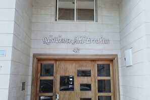 A building entrance with a sign reading 'Résidence Allé Erolin 42' above a wooden door with multiple glass panels. - Hassan II Mosque Casa International Fair (Casablanca)