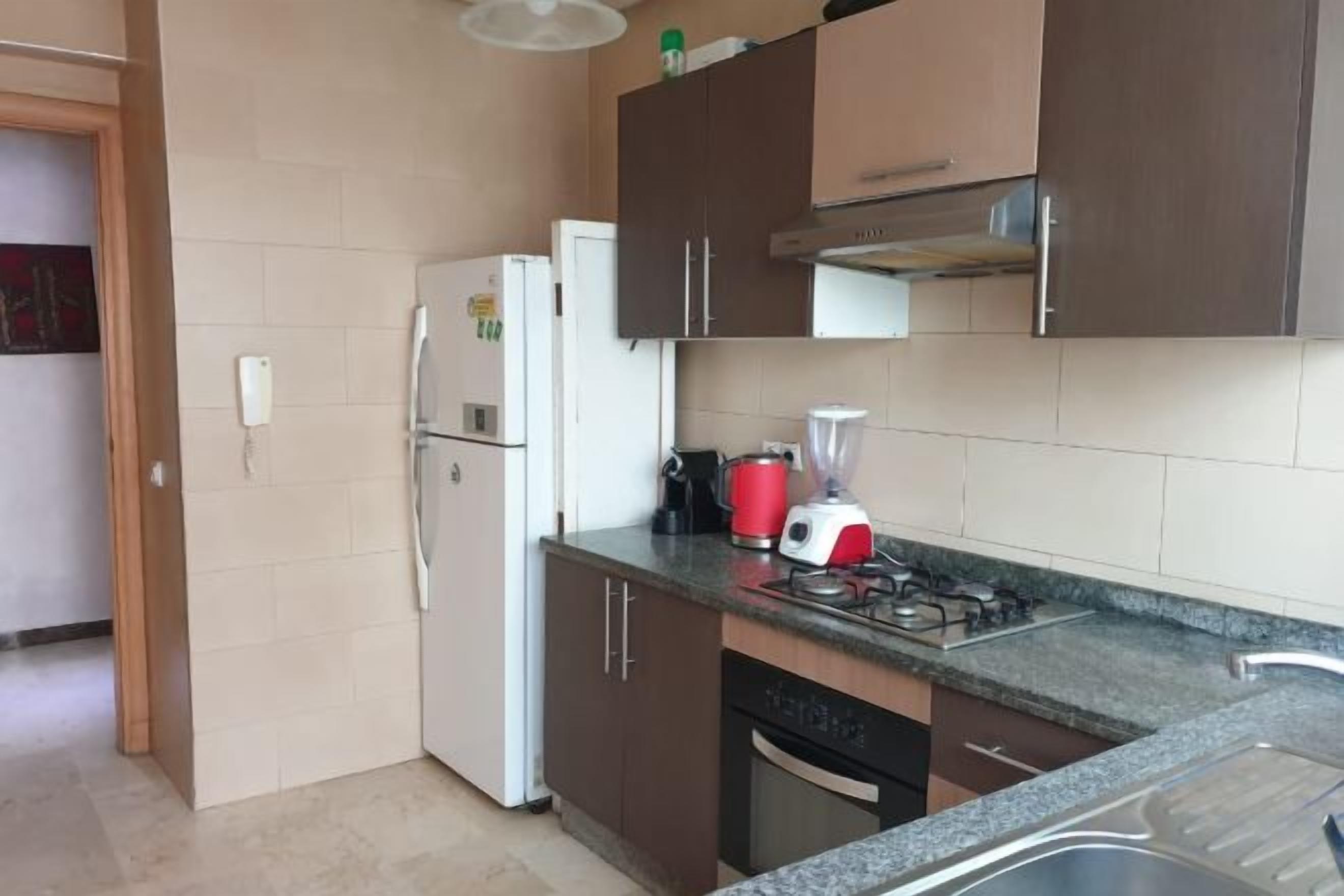 Una cocina con refrigerador, estufa, lavaplatos y gabinetes.