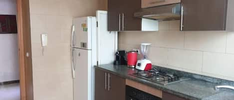 Una cocina con refrigerador, estufa, lavaplatos y gabinetes.