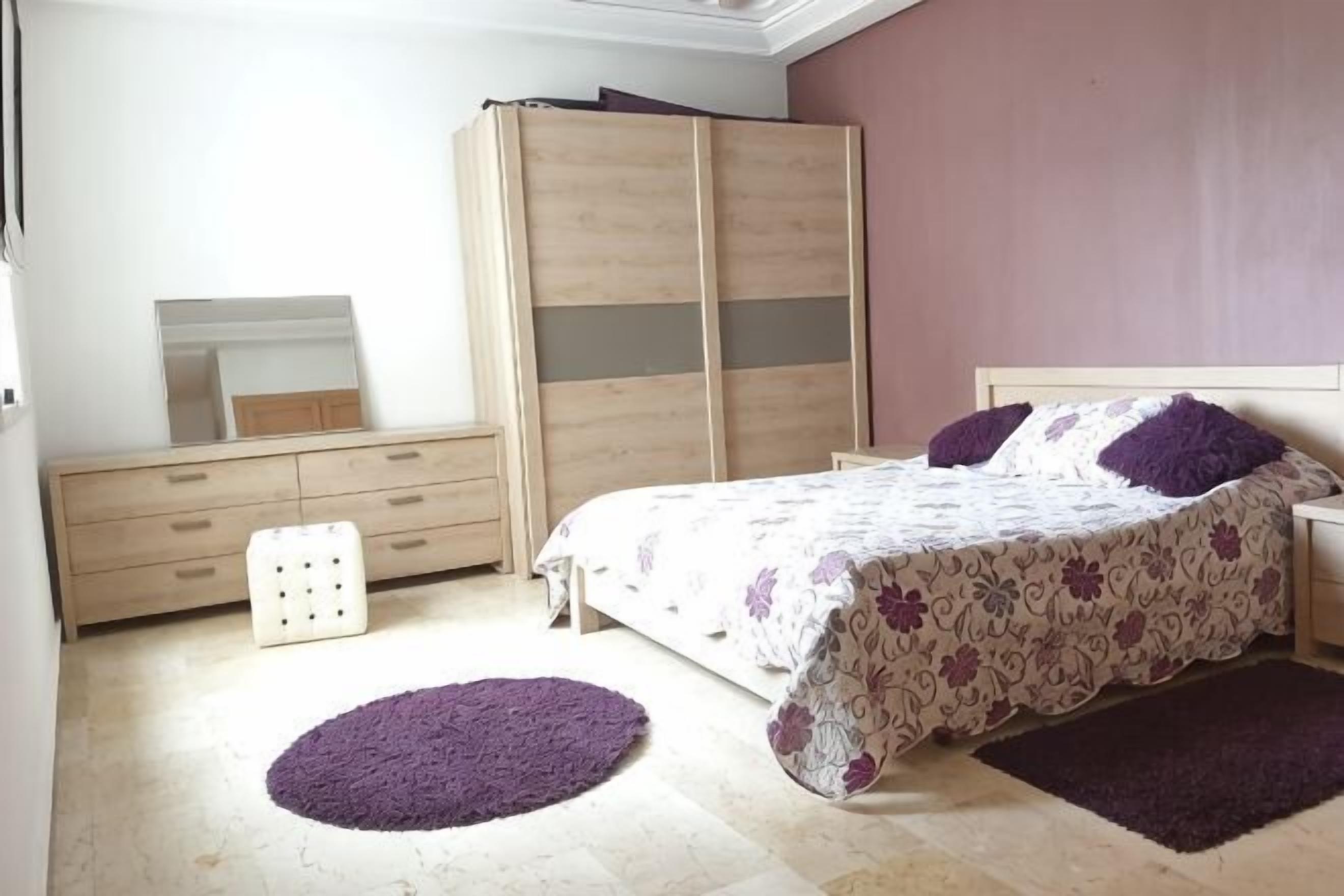 A bedroom with a bed, dresser, mirror, and a large wardrobe.