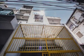 A multi-story building with a yellow gate, balconies, and visible windows. - CAMP Dakao a curated accomodation (Ho Chi Minh City)