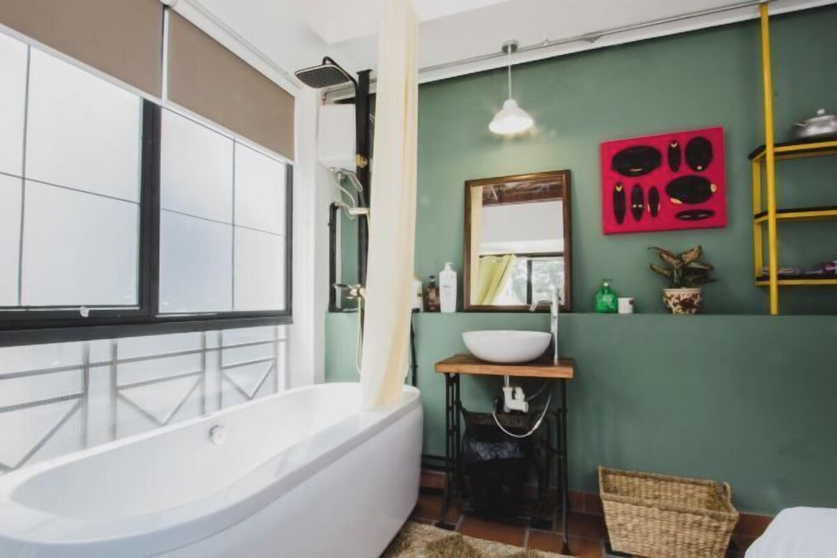 Un baño moderno con una bañera independiente, un lavamanos pequeño y un espejo encima.