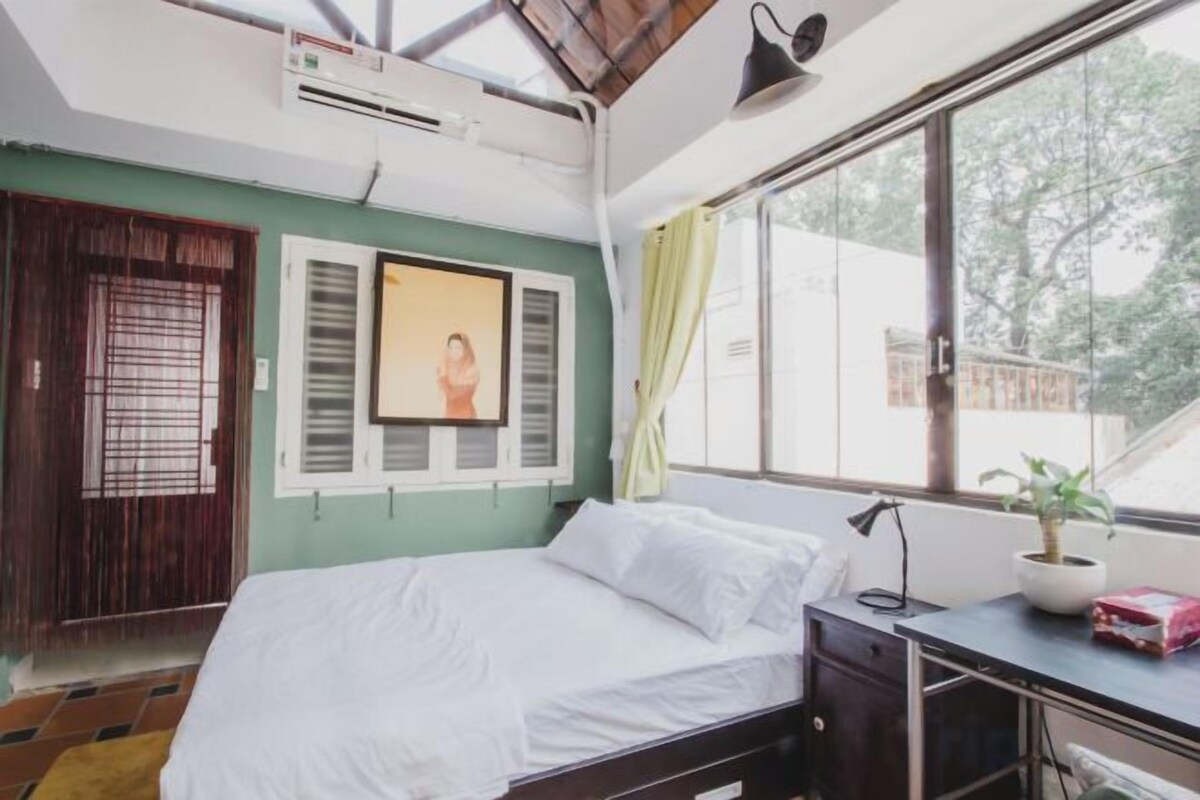Un dormitorio con cama, escritorio, ventana y planta en maceta.