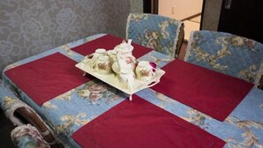 A dining table with floral upholstery and red placemats, set with a tea set.