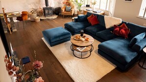 Un salon moderne avec un canapé d’angle bleu, une table basse ronde et une cheminée.
