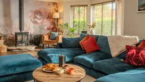 Un salon chaleureux avec un canapé bleu, une table basse sur laquelle sont posés des croissants et une cheminée.