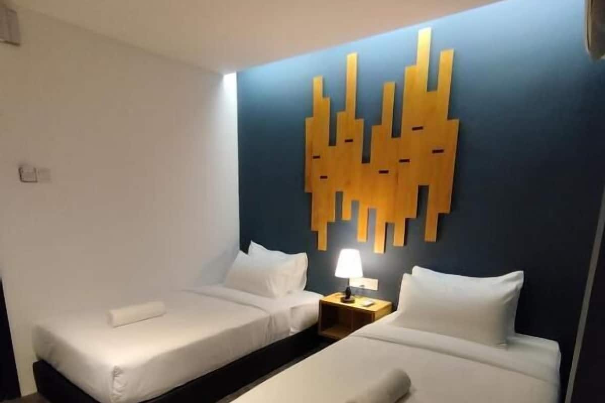 A hotel room with two beds, a modern wall art piece, and a nightstand with a lamp.