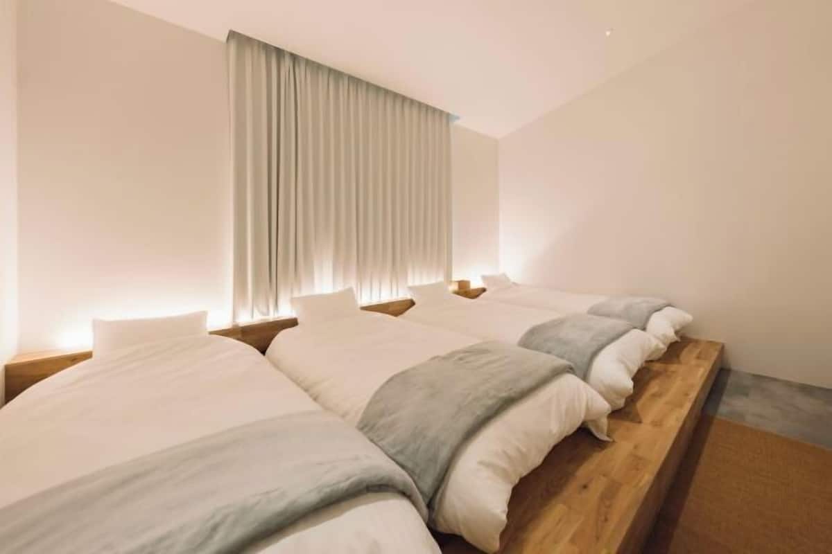 A hotel room with a long wooden bed, a large window with curtains, and a simple, clean design.