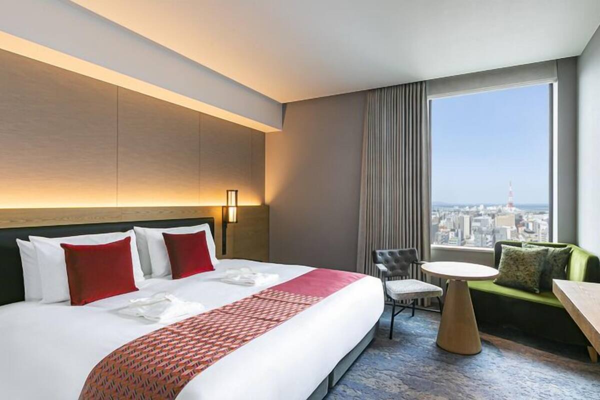A hotel room with a large bed, a small round table, a sofa, and a TV.