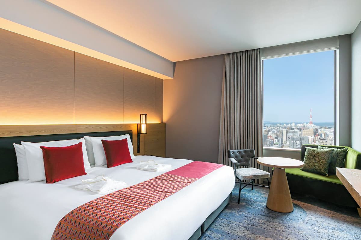 A hotel room with a large bed, a small round table, a sofa, and a TV.