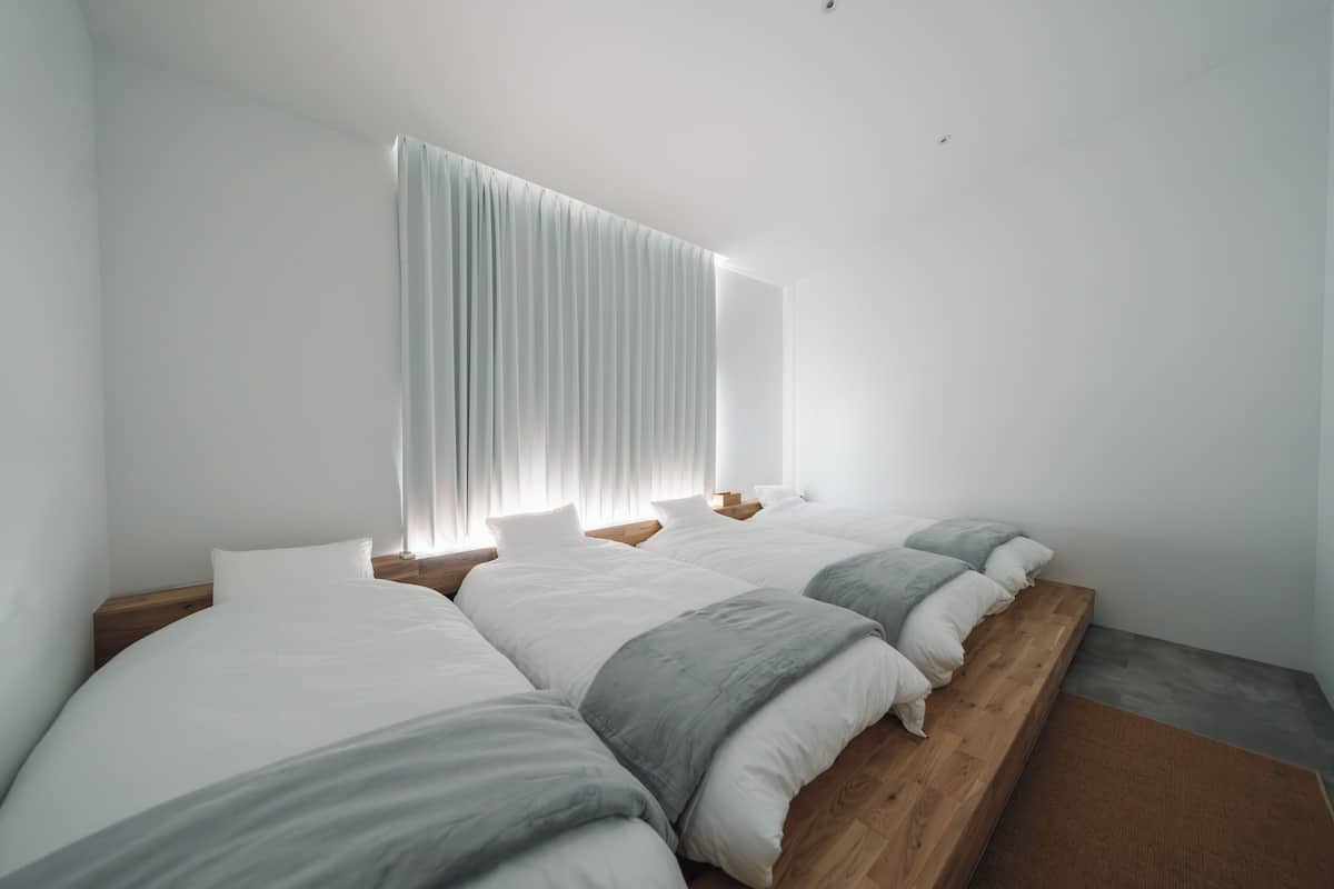 A bedroom with a large bed, a wooden platform, and a window with curtains.