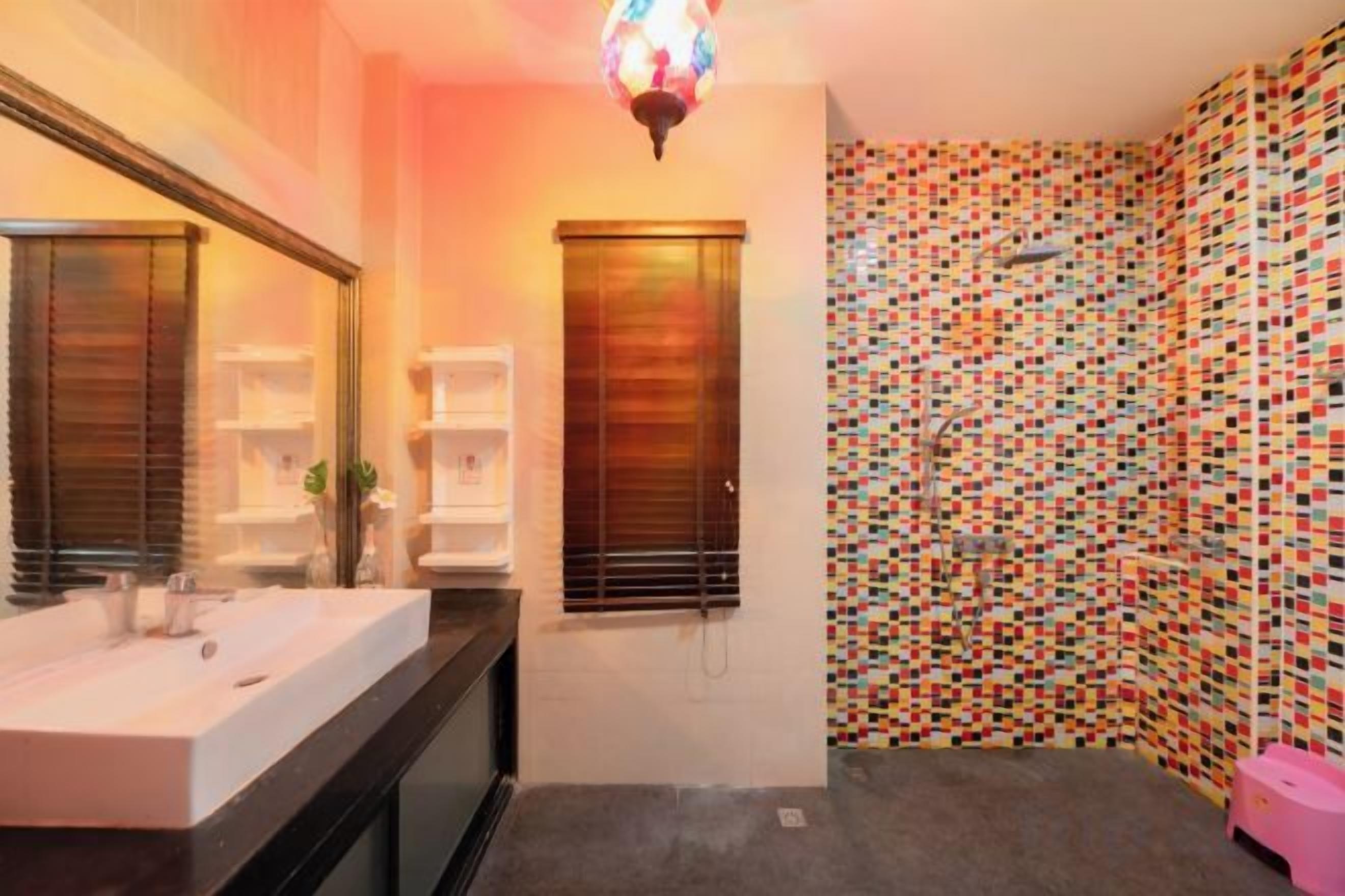 Un bagno con un ampio specchio, un lavandino e una zona doccia.