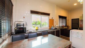 A compact kitchen with a dining table, a microwave, a coffee maker, and a refrigerator. - DayDream Pool Villa (Bang Lamung)