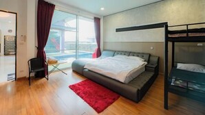 A modern bedroom with a large bed, a bunk bed, a red rug, and a view of the outdoors. - DayDream Pool Villa (Bang Lamung)