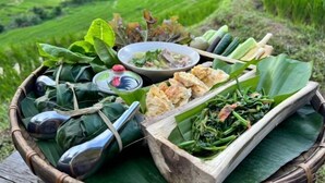 A traditional meal setup with food wrapped in leaves, a bowl of soup, and a basket of vegetables. - Hae o bi (rice terraces) (Samoeng)