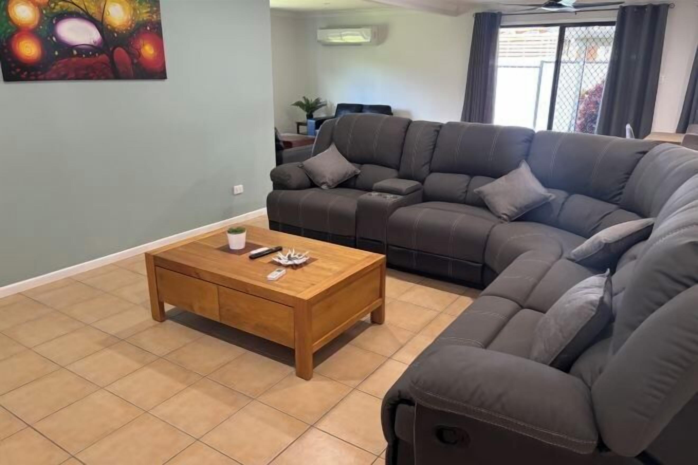 Una sala de estar con un sofá modular, una mesa de centro de madera y un cuadro en la pared.