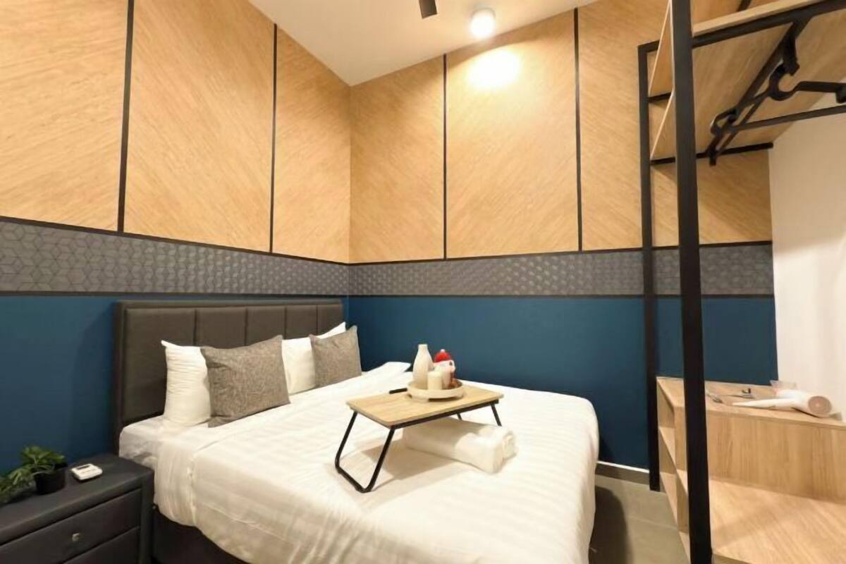 Una habitación de hotel moderna con cama, mesita de noche y un pequeño escritorio con silla.
