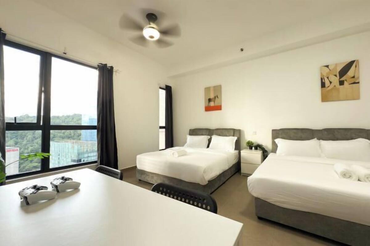 Habitación de hotel con dos camas, un escritorio y un ventanal grande con vistas a la ciudad.
