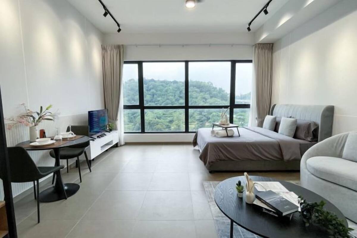 Una habitación de hotel moderna con un ventanal grande, una cama, un sofá, un escritorio con una silla y una mesa de centro.