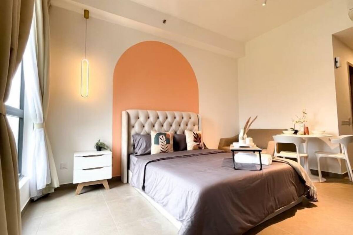 Un dormitorio moderno con un cabecero capitonado, una mesita de noche, un escritorio y una silla.