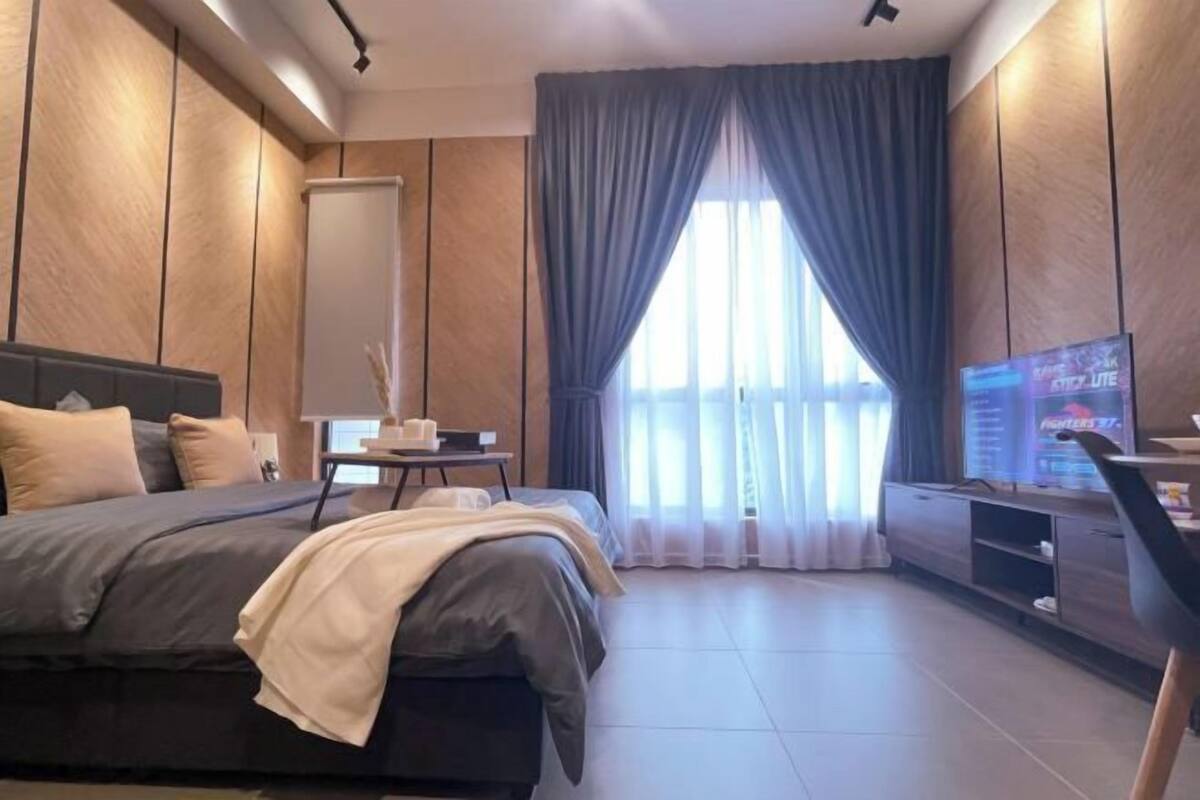 Una habitación de hotel moderna con una cama grande, un televisor y un escritorio con una lámpara.