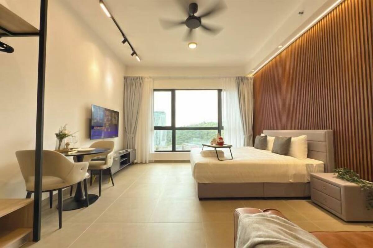 Una habitación de hotel moderna con una cama grande, un escritorio, una silla y vistas de la ciudad a través de un ventanal.