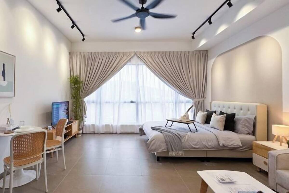 Una habitación de hotel moderna con una cama, un escritorio, una silla, un televisor y un ventilador de techo.