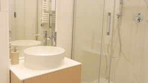 Ein modernes Badezimmer mit zwei Waschbecken, einer Glasdusche und einem Spiegel.