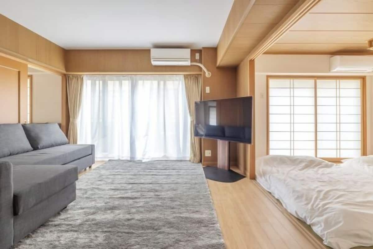 Ein Hotelzimmer mit einer Couch, einem Bett, einem Fernseher und einer Schiebetür.