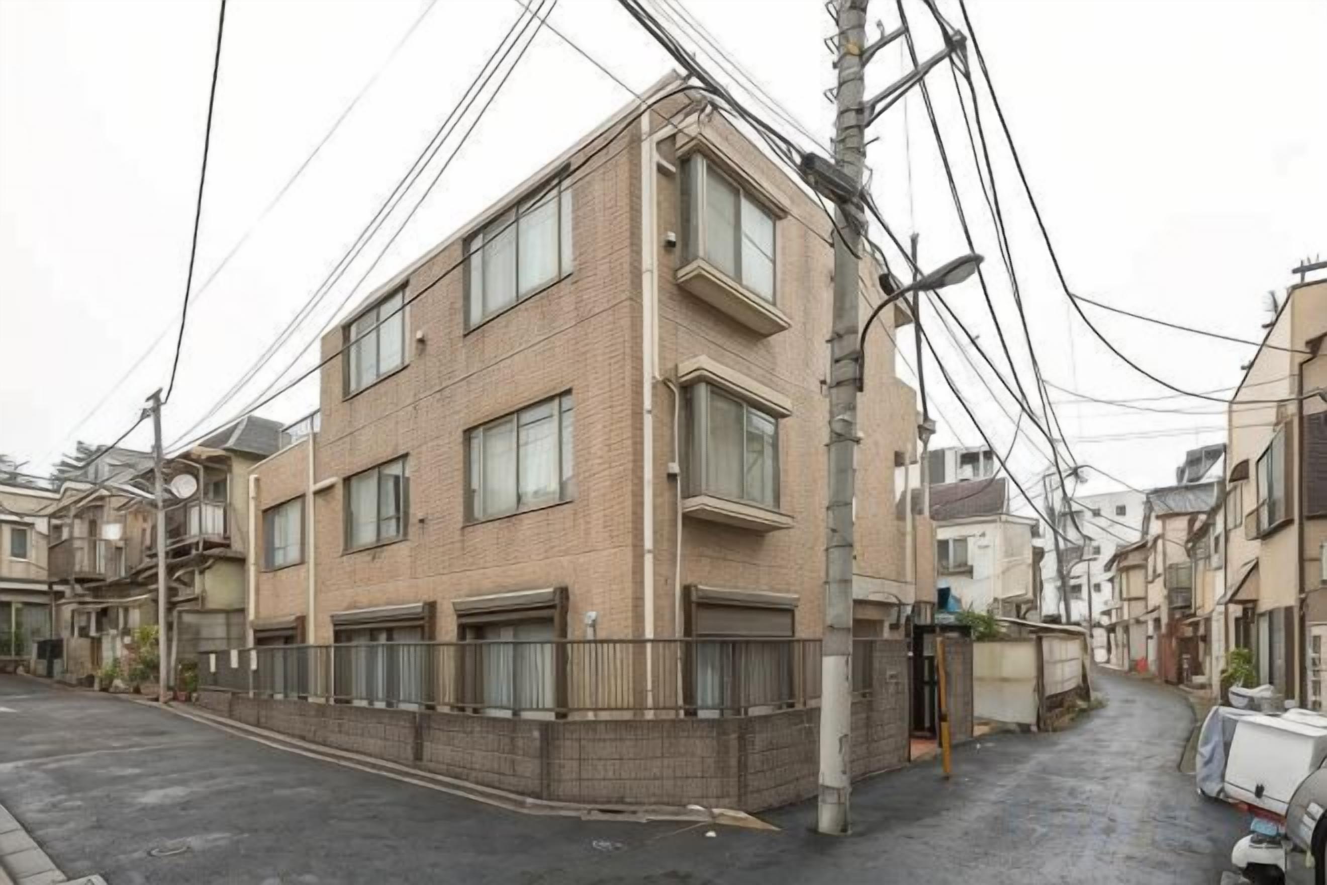 A multi-story residential building with a brick facade, multiple windows, and a gated entrance.