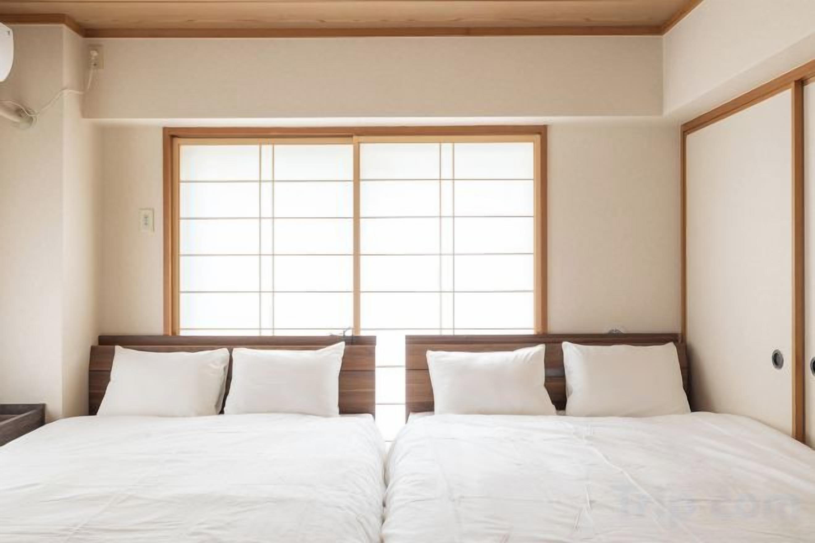 A room with two beds, wooden headboards, and a large window with a grid pattern.