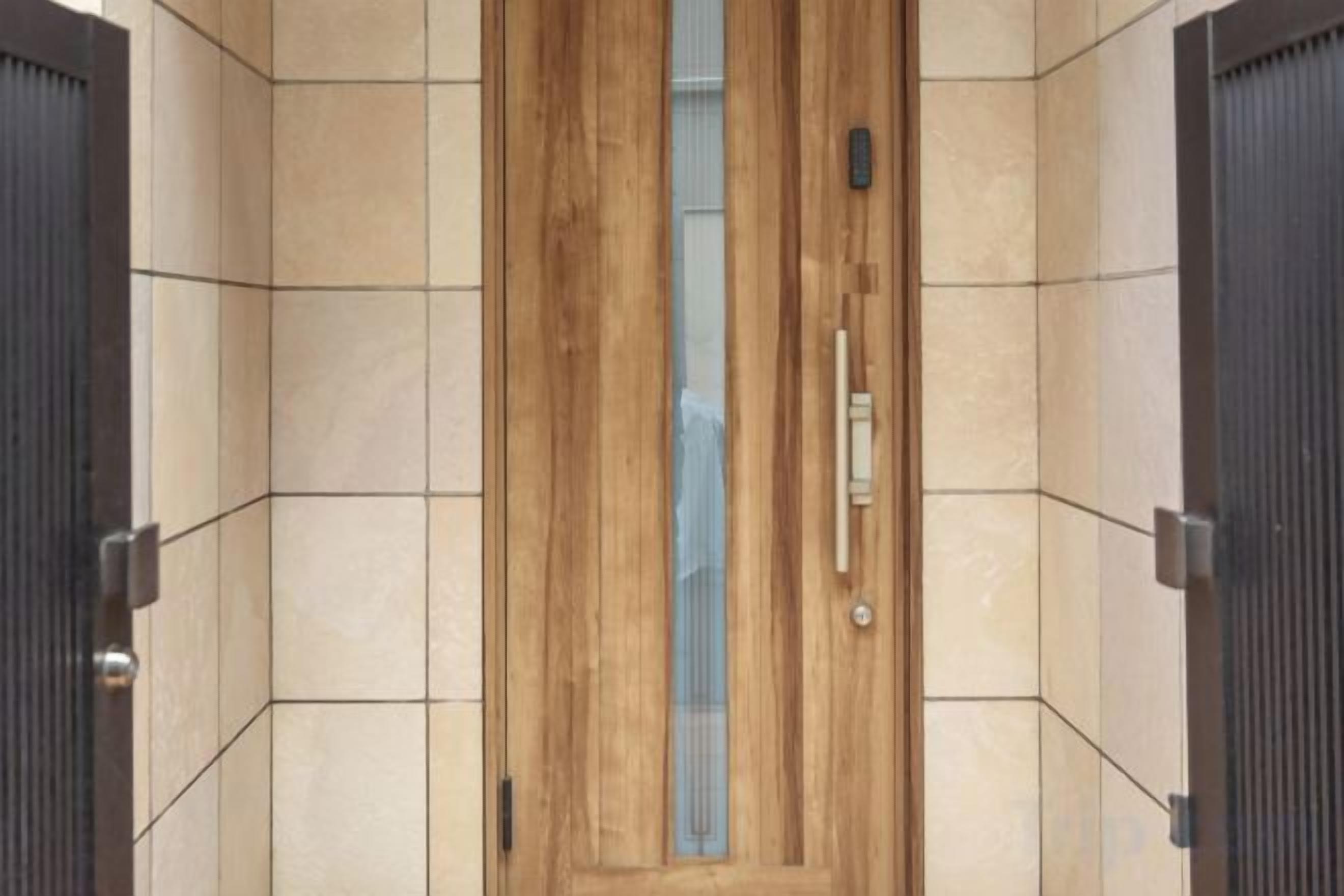 A wooden door with a handle and a keyhole, set in a tiled wall.