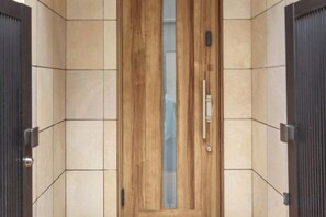 Eine Holztür mit Griff und Schlüsselloch in einer gefliesten Wand.