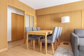 A room with a wooden dining table and chairs, a sofa, a lamp, and a door. - HAN HOTEL Shinjuku (Tokyo)
