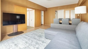 Un soggiorno moderno con un divano grigio, una TV a schermo piatto e un pavimento in legno.