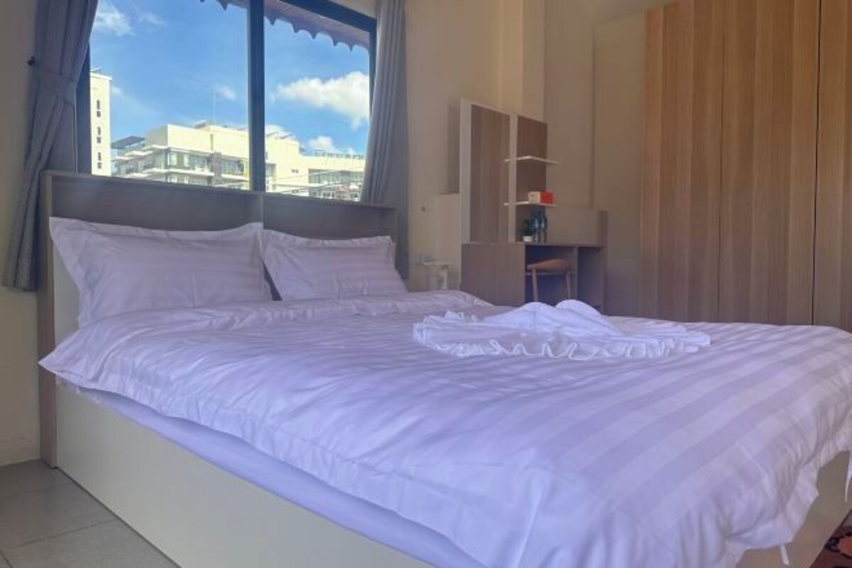 A hotel room with a large bed, a wardrobe, and a window with a view of buildings.
