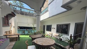 An outdoor patio area with a round table and chairs, surrounded by potted plants and a small fountain.