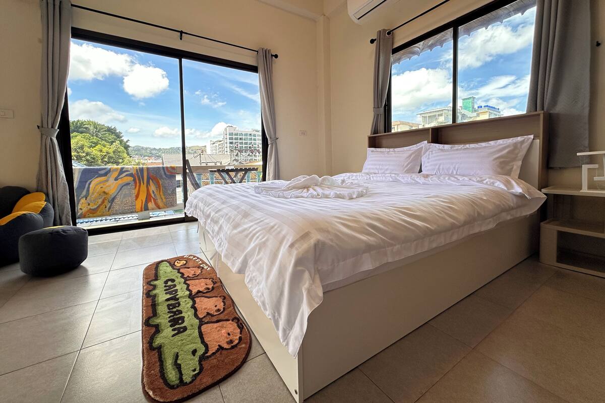 A hotel room with a large bed, a view of the city, and an air conditioning unit.