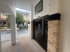 Une entrée d’immeuble avec une porte en verre, une façade en pierre et une enseigne au-dessus de la porte.