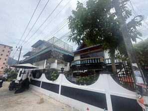 Un immeuble à plusieurs étages doté de balcons, d’une entrée sécurisée et d’un arbre devant.