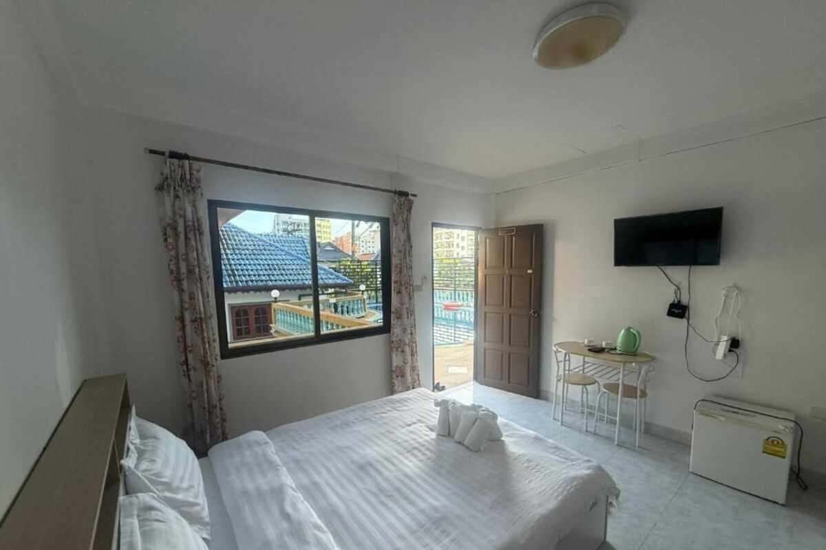 Une chambre d’hôtel comprenant un lit, une télévision, un bureau avec une chaise et une fenêtre avec des rideaux.