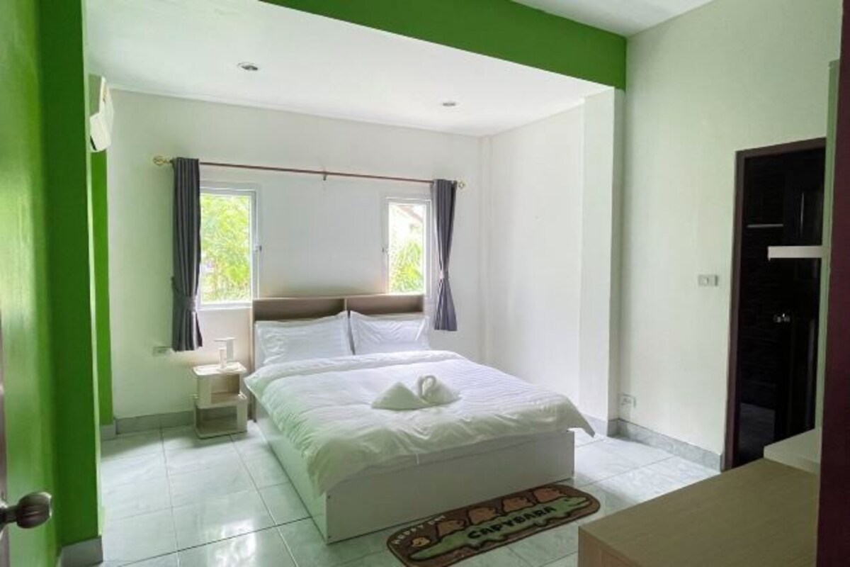 A bedroom with a bed, a nightstand, a window with curtains, and a door.