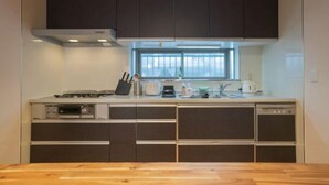A modern kitchen with dark cabinets, a window, and a countertop with a toaster and other appliances. - STAY OSAKA KUROMON Walkable to Namba, Shinsaibashi, and Dotonbori 14-minute train ride to USJ (Osaka)