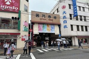 A busy street with a market entrance, pedestrians crossing, and various storefronts. - STAY OSAKA KUROMON Walkable to Namba, Shinsaibashi, and Dotonbori 14-minute train ride to USJ (Osaka)