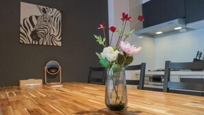 A wooden dining table with a clear glass vase containing flowers. A zebra print artwork is visible on the wall behind the table. - STAY OSAKA KUROMON Walkable to Namba, Shinsaibashi, and Dotonbori 14-minute train ride to USJ (Osaka)