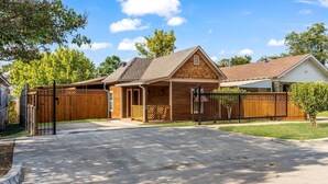 A residential house with a wooden exterior, a fenced backyard, and a driveway leading to the front door.