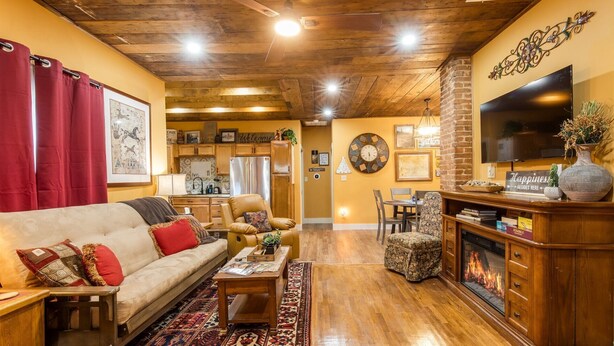 A cozy living room with a fireplace, a sofa, a coffee table, and a dining area.