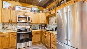 A kitchen with wooden cabinets, stainless steel appliances, a microwave, a stove, and a refrigerator.