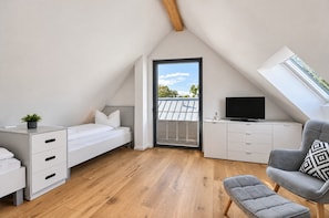 Une chambre de style loft moderne, avec un plafond en pente, un lit, un bureau, une chaise et un téléviseur.
