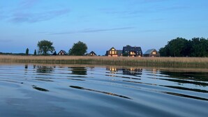 A row of houses by a calm water body with a clear sky. - House "LUV" on the lake in Streu (Bergen auf Rügen)